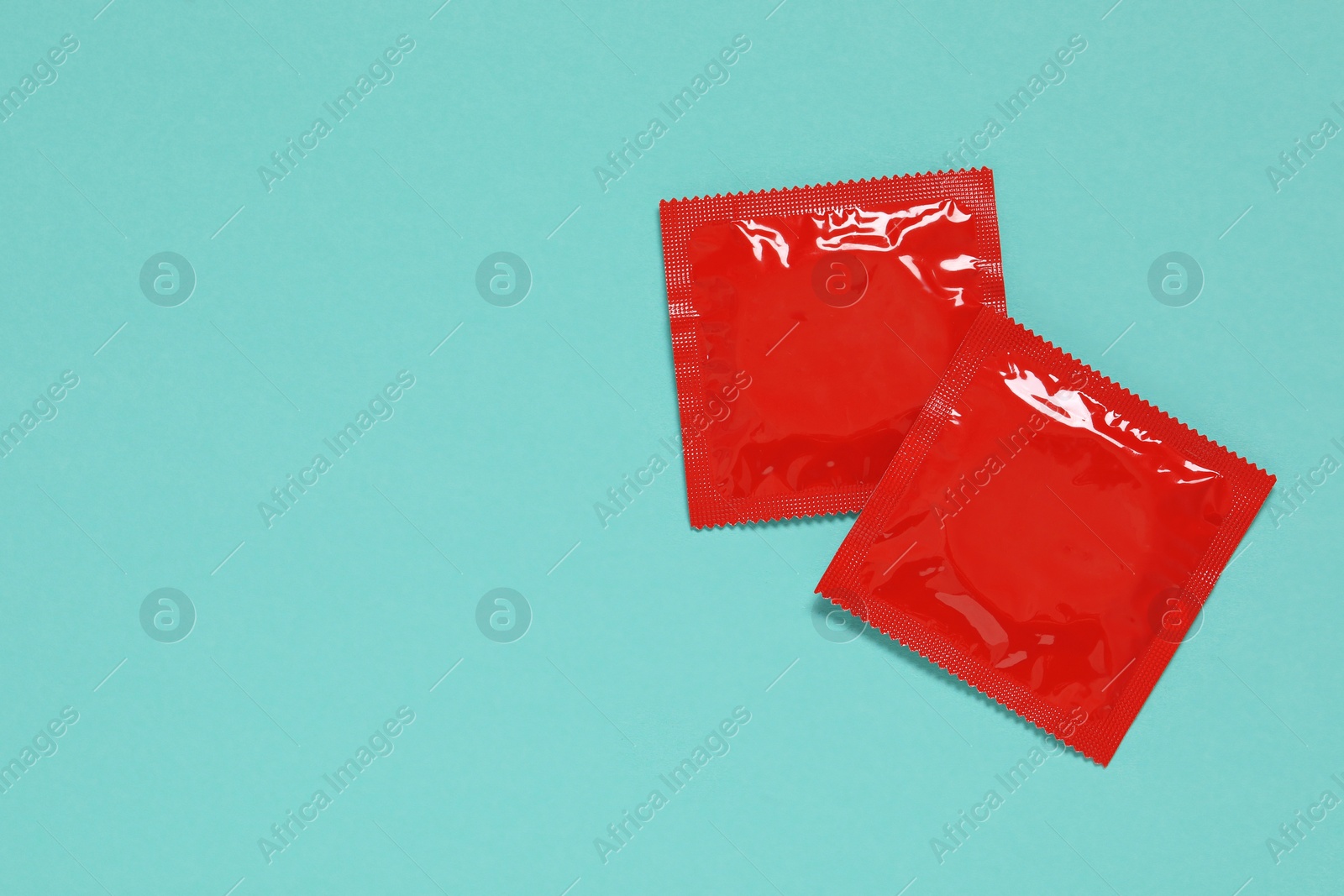 Photo of Condom packages on turquoise background, flat lay and space for text. Safe sex