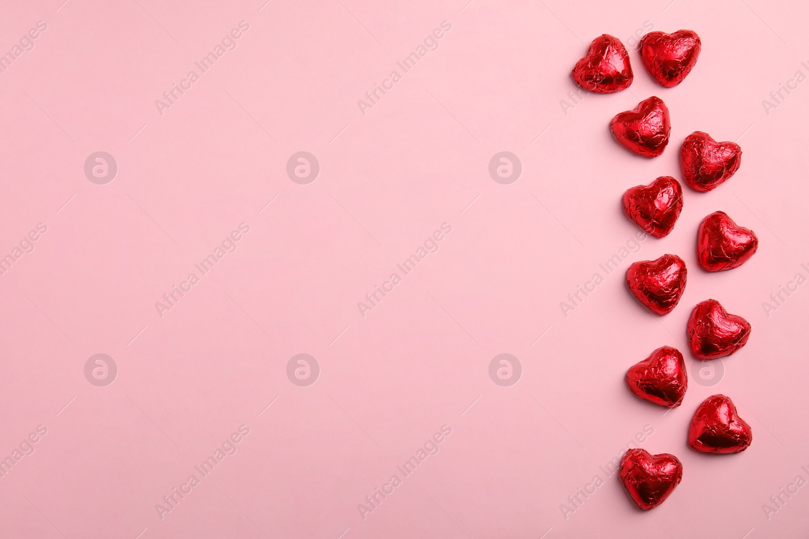 Photo of Heart shaped chocolate candies on pink background, flat lay with space for text. Valentine's day treat