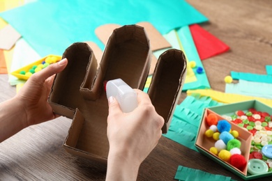 Woman making cardboard cactus at wooden table, closeup. Pinata DIY