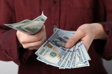 Woman counting dollar banknotes on light background, closeup