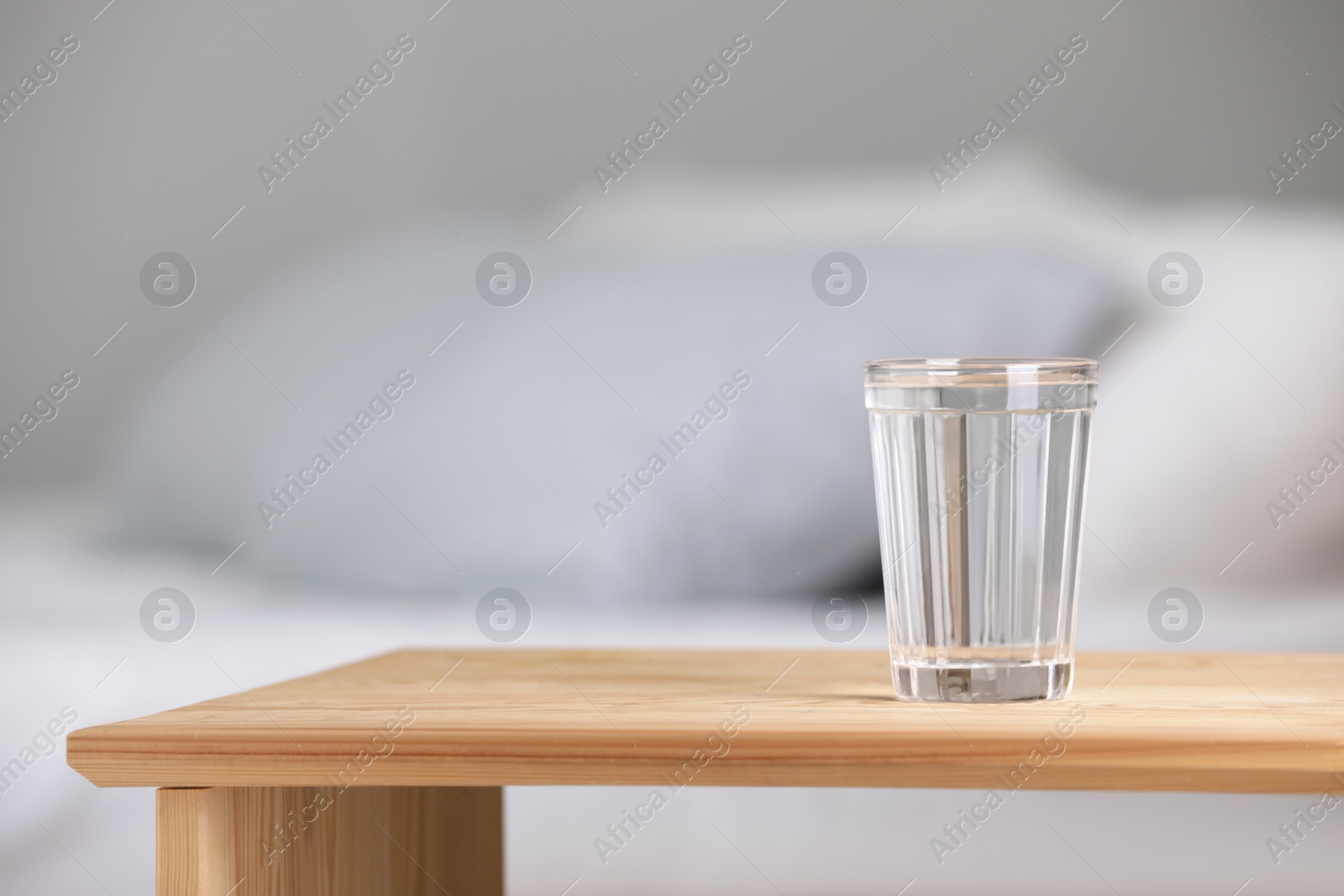 Photo of Glass of pure water on wooden table indoors. Space for text