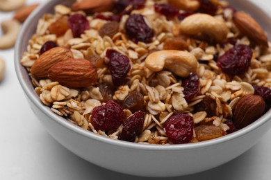 Bowl of tasty granola with nuts and dry fruits on white marble table, closeup