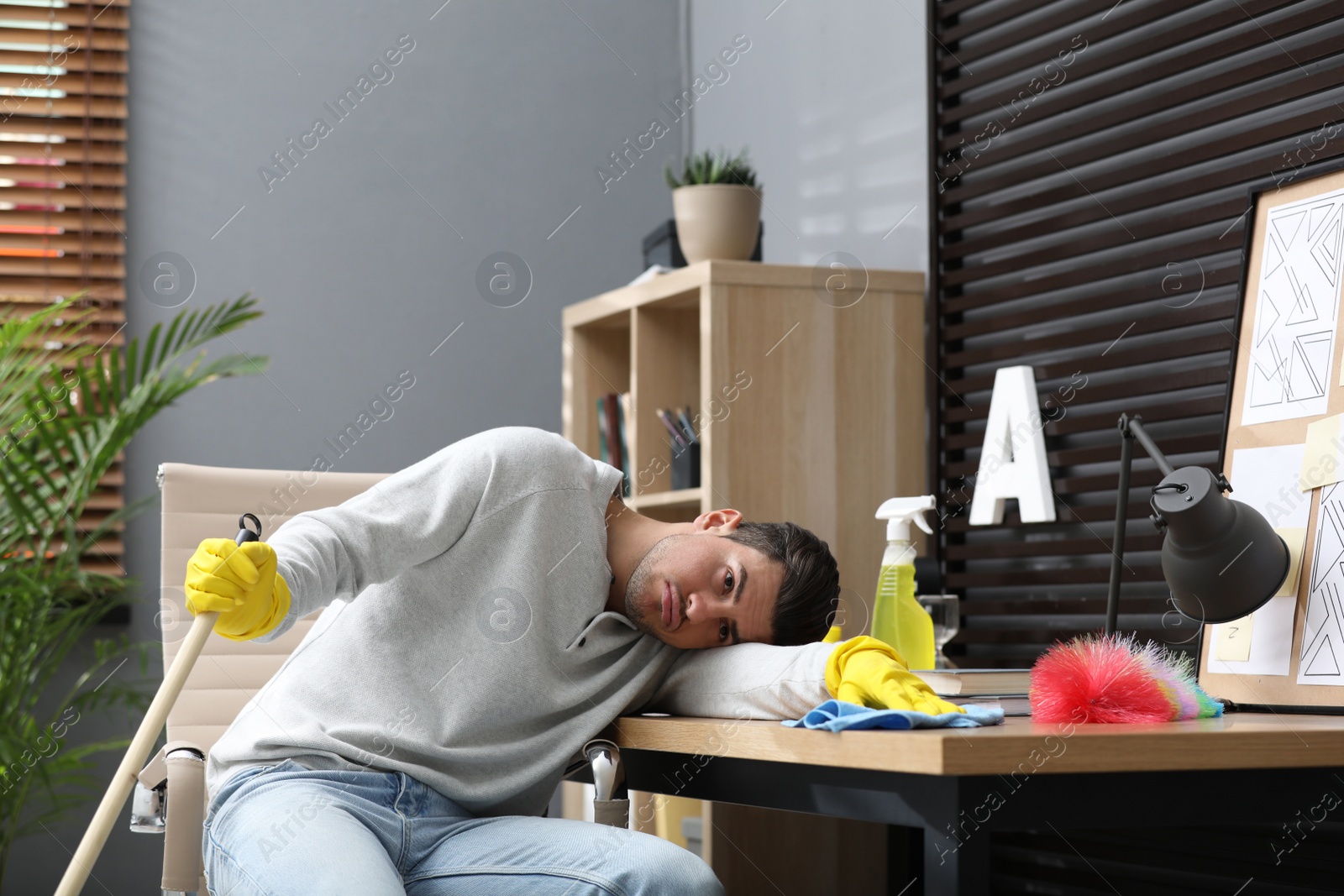 Photo of Lazy man procrastinating while cleaning at home