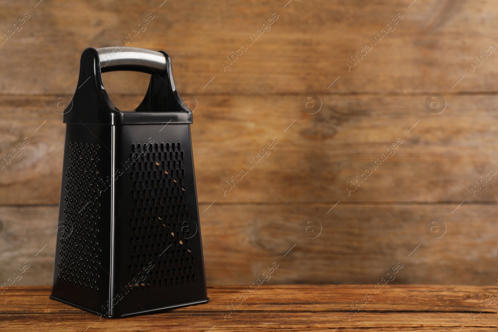 Photo of Modern black grater on wooden table. Space for text
