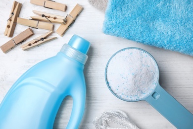 Flat lay composition with laundry detergents, clothespins and towels on white wooden background