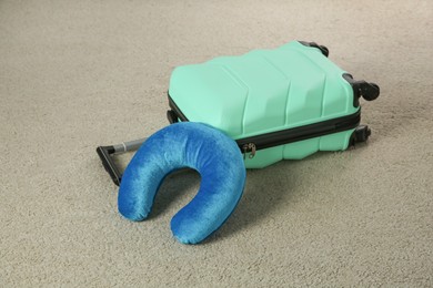 Photo of Light blue travel pillow and suitcase on beige rug