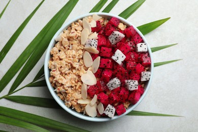 Photo of Bowl of granola with pitahaya and almond petals on light table, top view