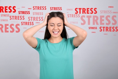 Stressed young woman and text on light grey background