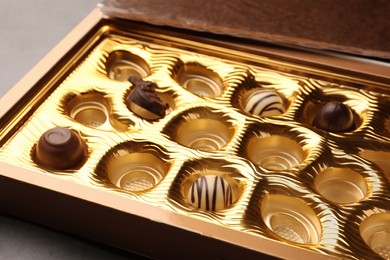 Partially empty box of chocolate candies on grey table, closeup