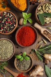 Photo of Different herbs and spices on wooden table, flat lay