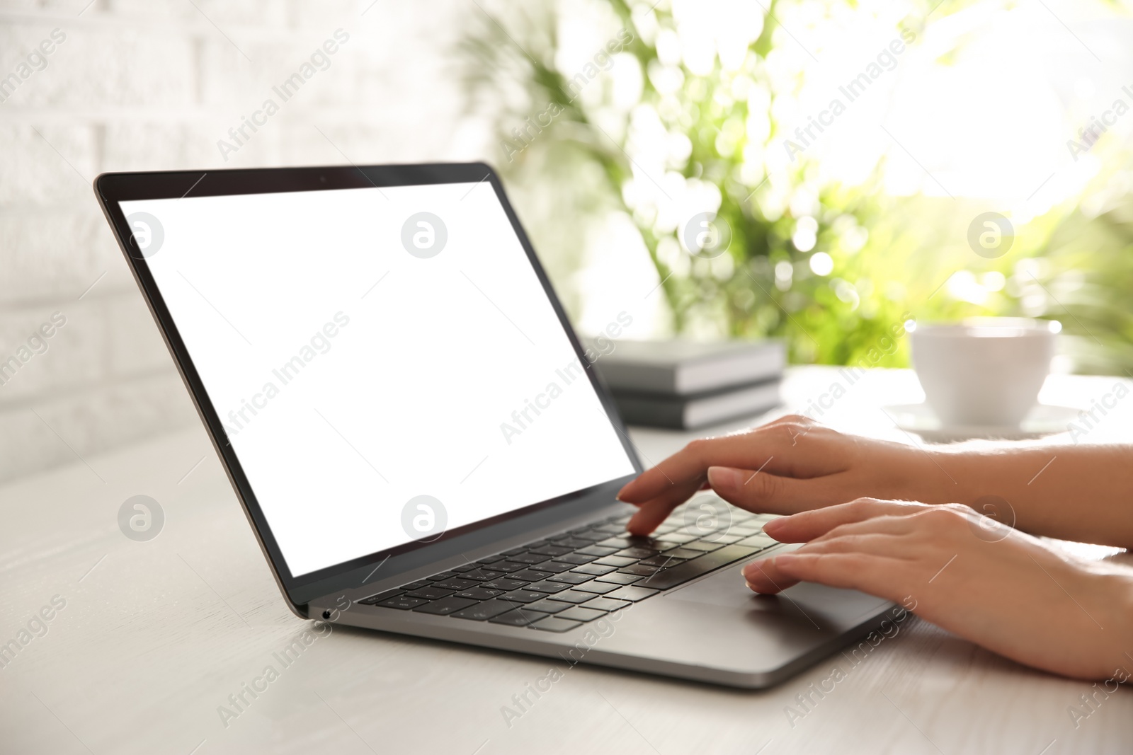 Photo of Woman working with modern laptop at white wooden table, closeup