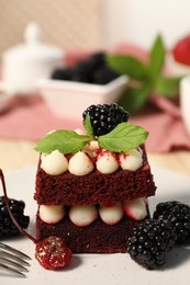 Photo of Piece of delicious red velvet cake with fresh berries on plate, closeup