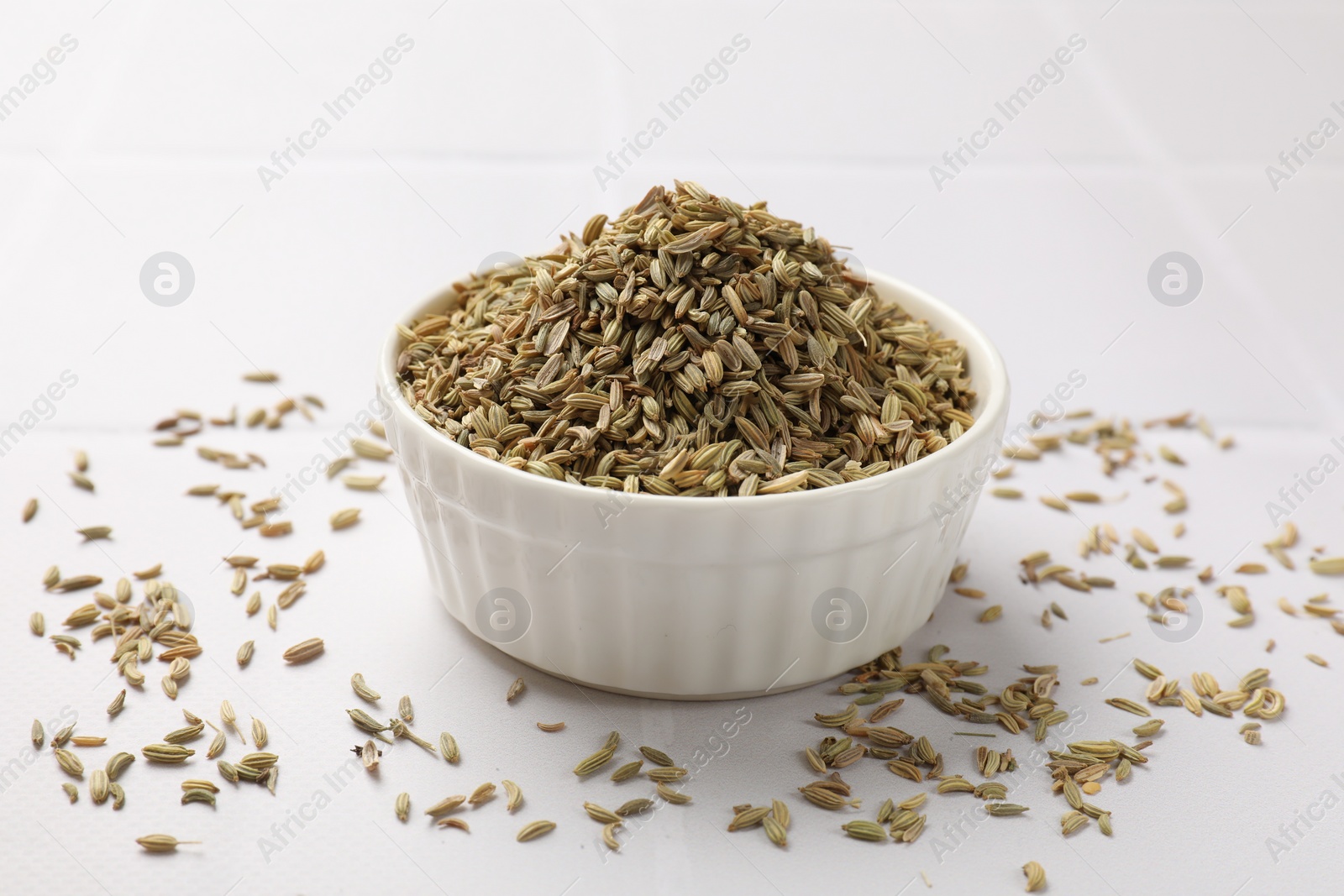 Photo of Bowl with fennel seeds on white table, closeup