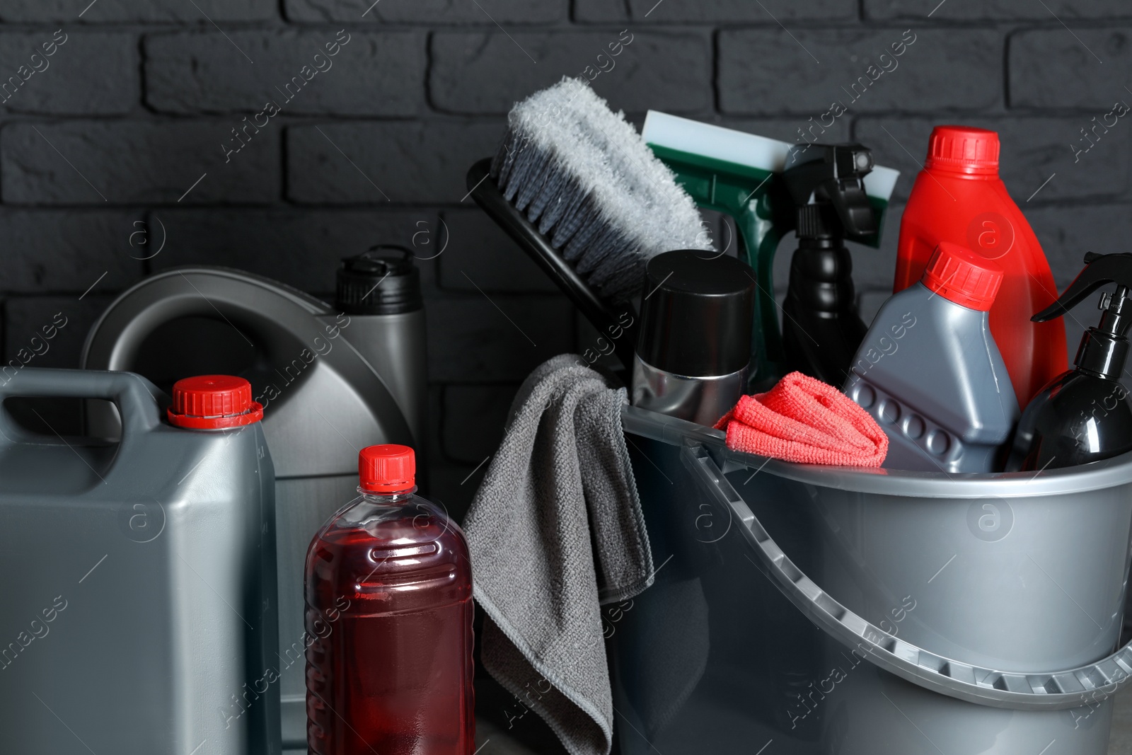 Photo of Different car cleaning products near black brick wall, closeup