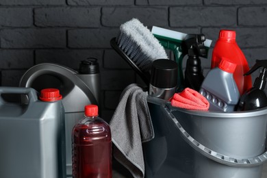 Different car cleaning products near black brick wall, closeup