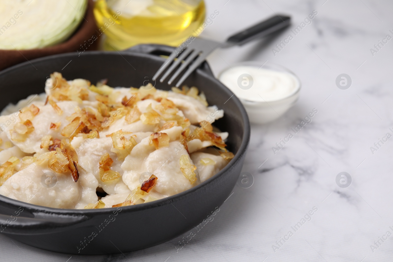 Photo of Cooked dumplings (varenyky) with tasty filling and fried onions on white marble table, closeup