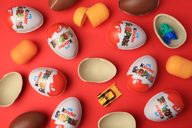 Sveti Vlas, Bulgaria - June 29, 2023: Kinder Surprise Eggs, plastic capsules and toys on red background, flat lay
