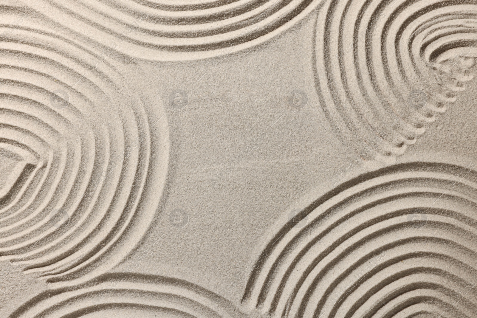 Photo of Beautiful patterns drawn on sand, top view. Zen garden