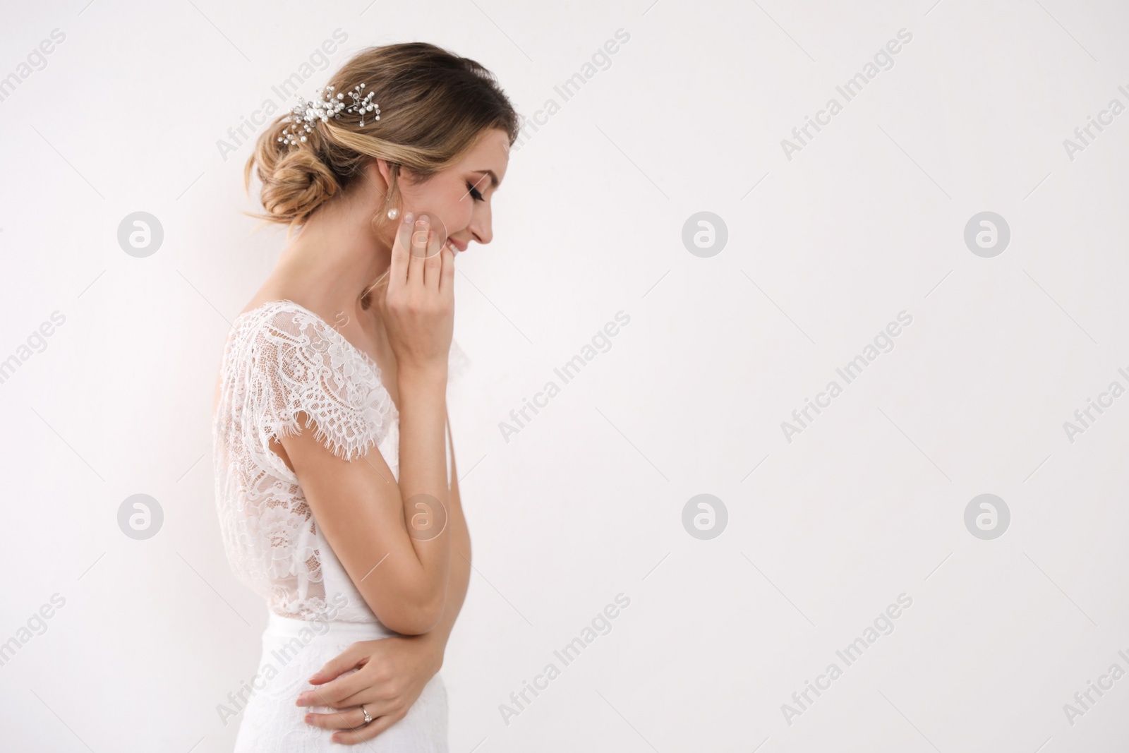 Photo of Young bride with elegant wedding hairstyle on light background. Space for text