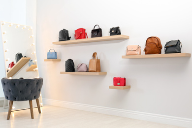 Photo of Stylish woman's bags on shelves in boutique