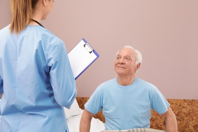 Nurse talking with senior man in hospital ward. Medical assisting