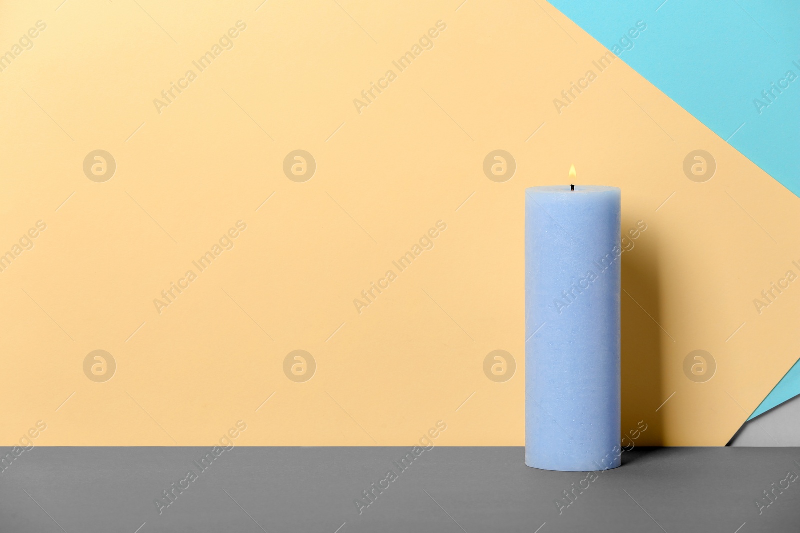 Photo of Decorative wax candle on table against color background