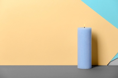 Photo of Decorative wax candle on table against color background