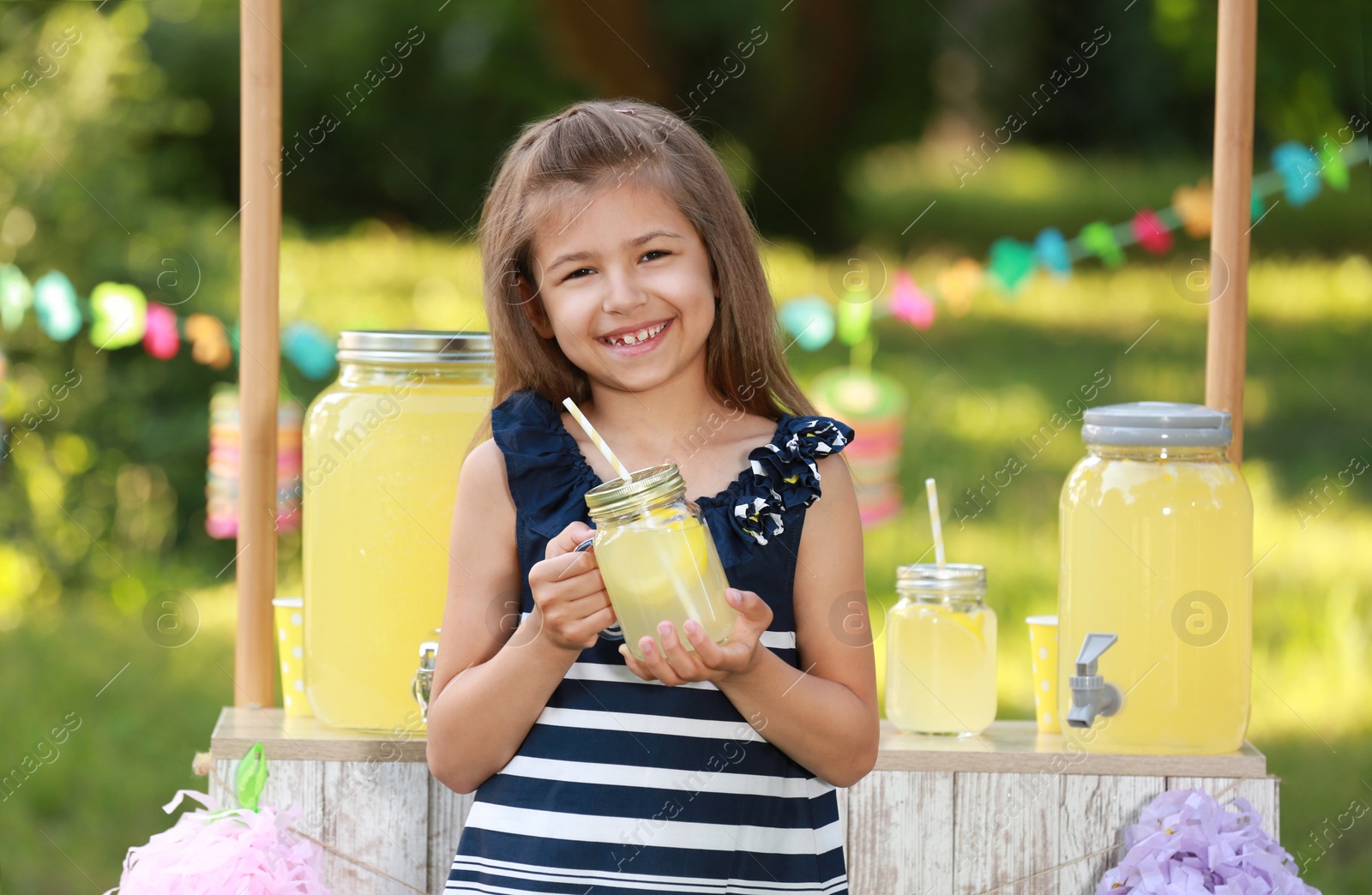 Photo of Cute little girl with natural lemonade in park. Summer refreshing drink