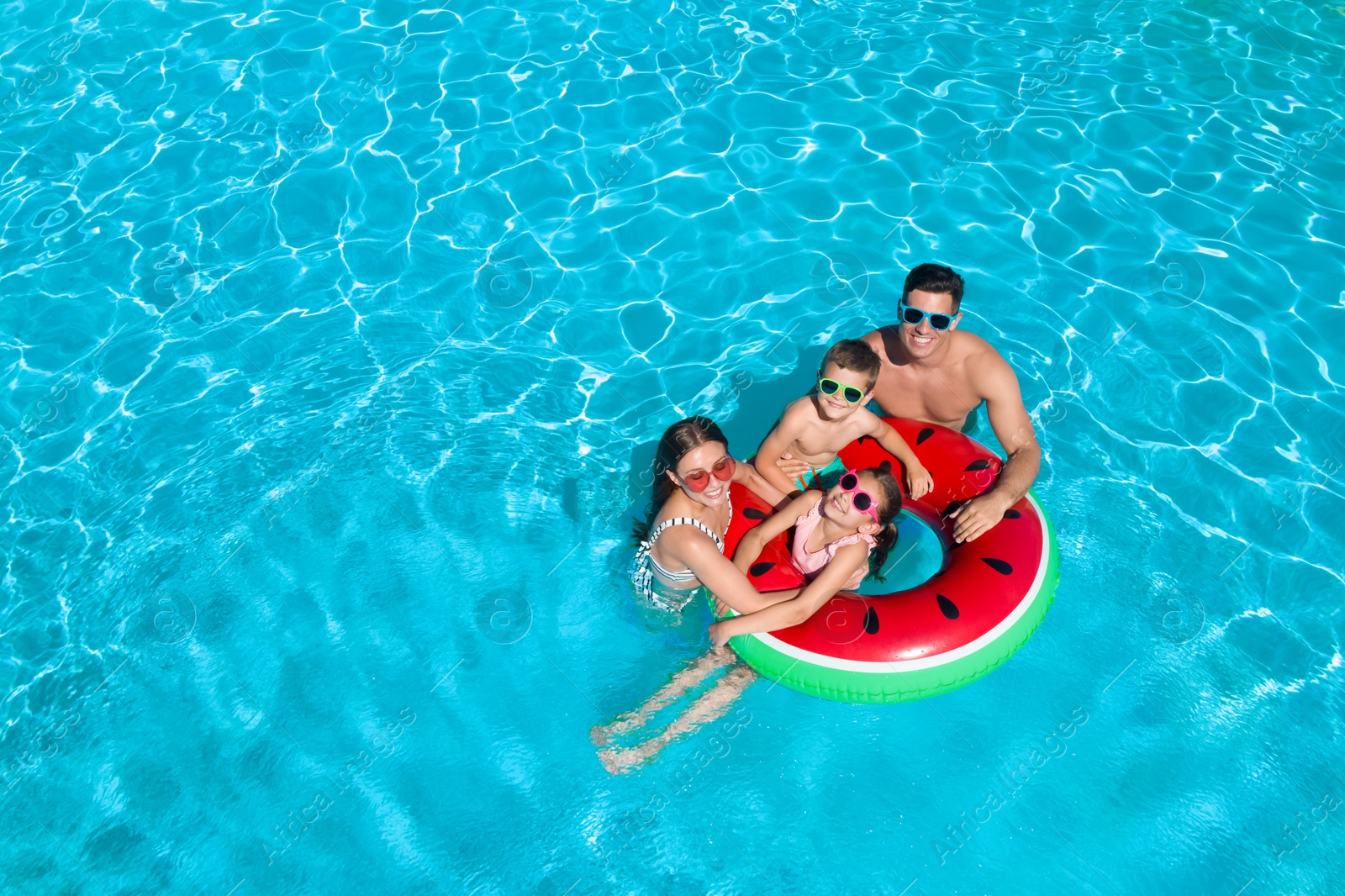 Image of Happy family with inflatable ring in swimming pool, space for text. Summer vacation 