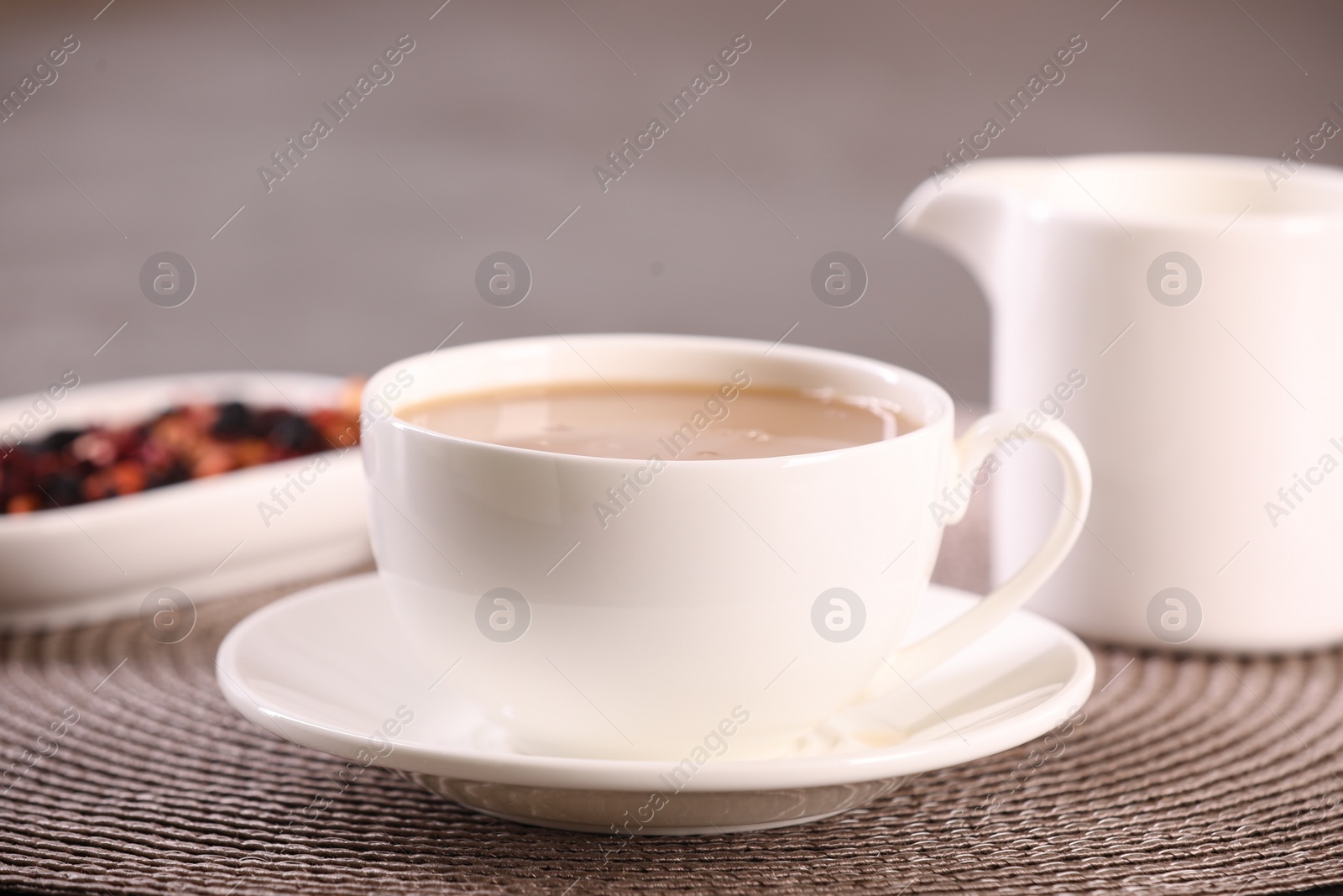 Photo of Cup of aromatic tea with milk and saucer on table, closeup
