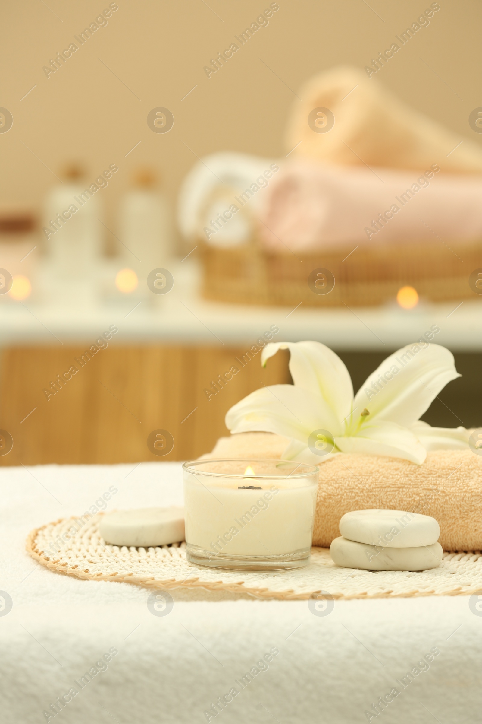 Photo of Beautiful spa composition with burning candle and stones on massage table in wellness center