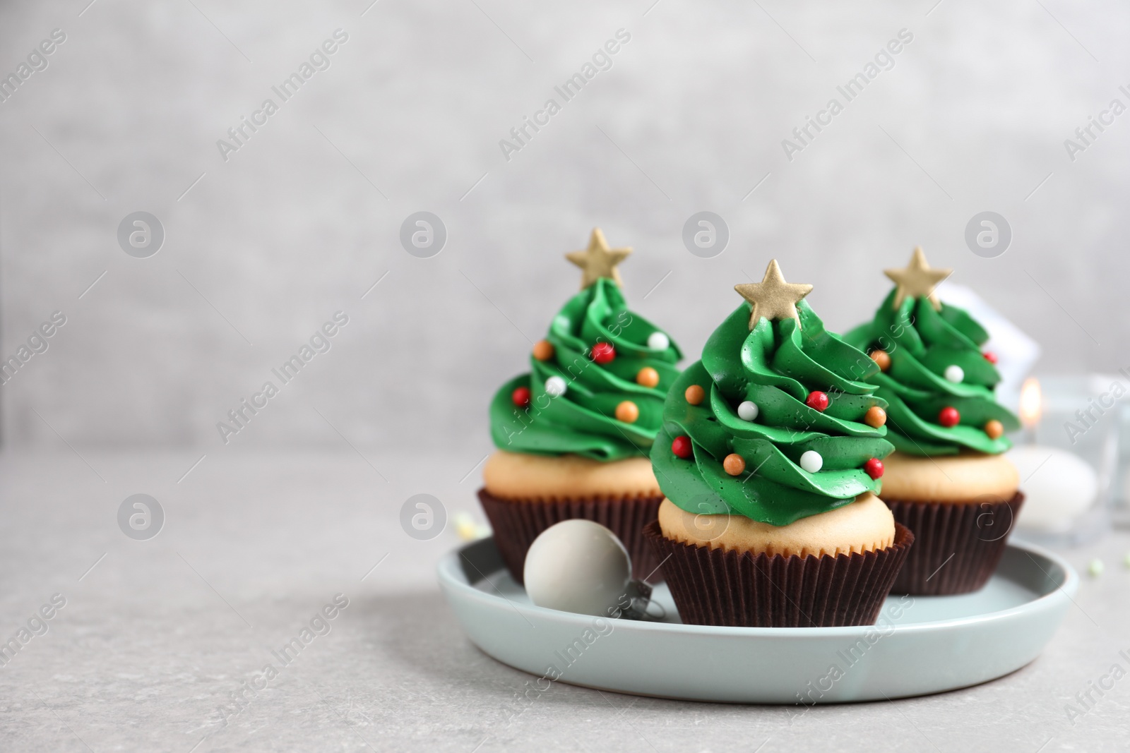 Photo of Christmas tree shaped cupcakes on light grey table. Space for text