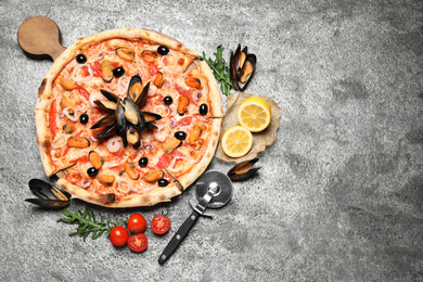 Tasty pizza with seafood and ingredients on grey table, flat lay. Space for text