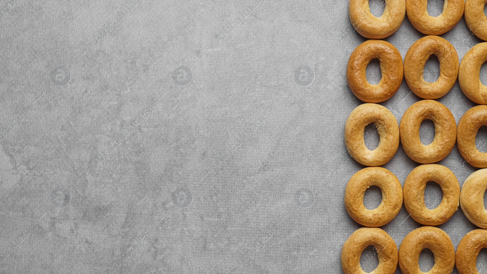 Photo of Many tasty dry bagels (sushki) on grey table, flat lay and space for text