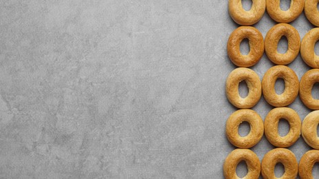 Many tasty dry bagels (sushki) on grey table, flat lay and space for text