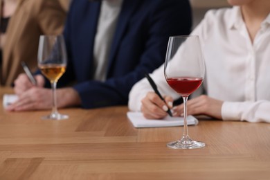 Photo of Sommeliers making notes during wine tasting at table indoors, closeup