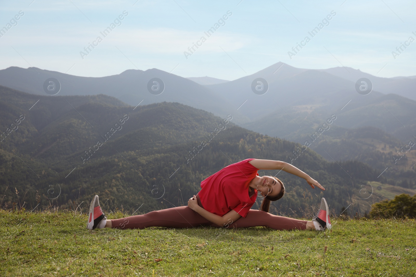 Photo of Young woman doing morning exercise in mountains, space for text