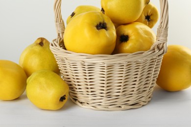 Photo of Basket with delicious fresh ripe quinces on white wooden table