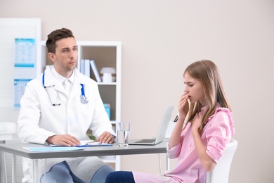 Coughing teenage girl visiting doctor at clinic
