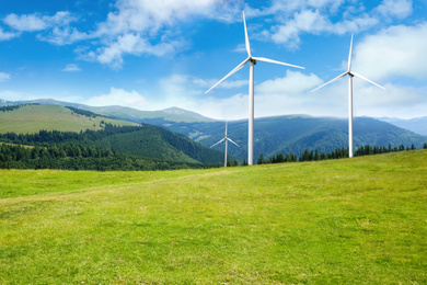 Image of Alternative energy source. Wind turbines in mountains under blue sky