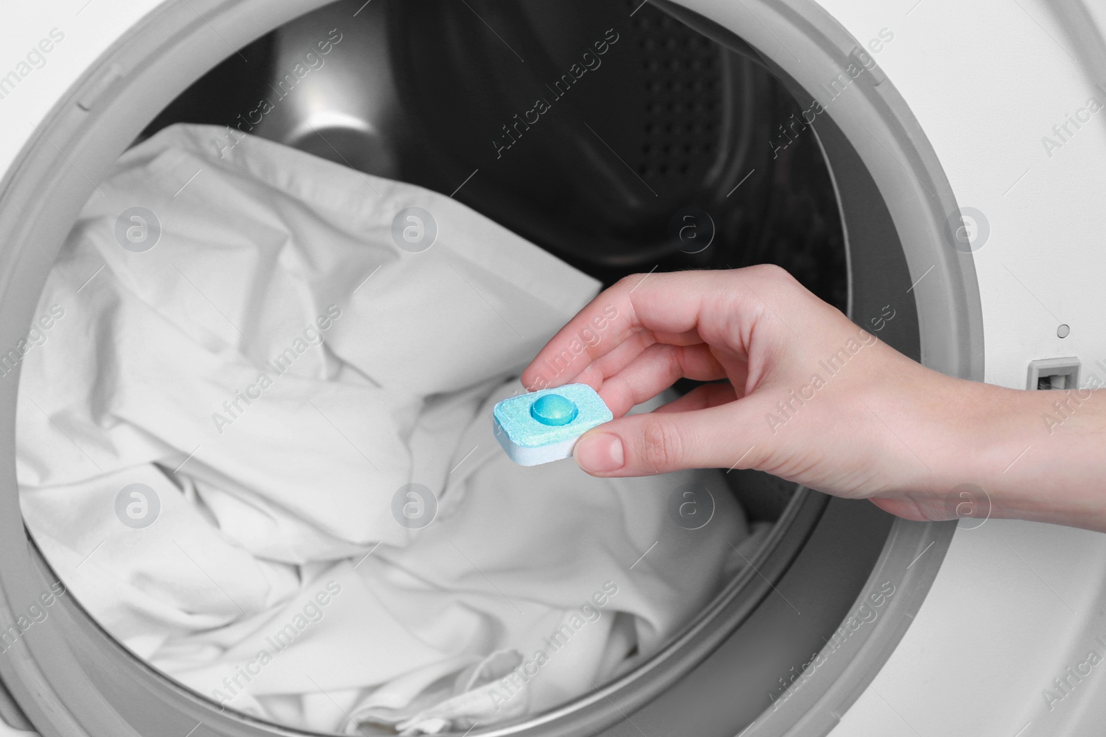 Photo of Woman putting water softener tablet into washing machine, closeup