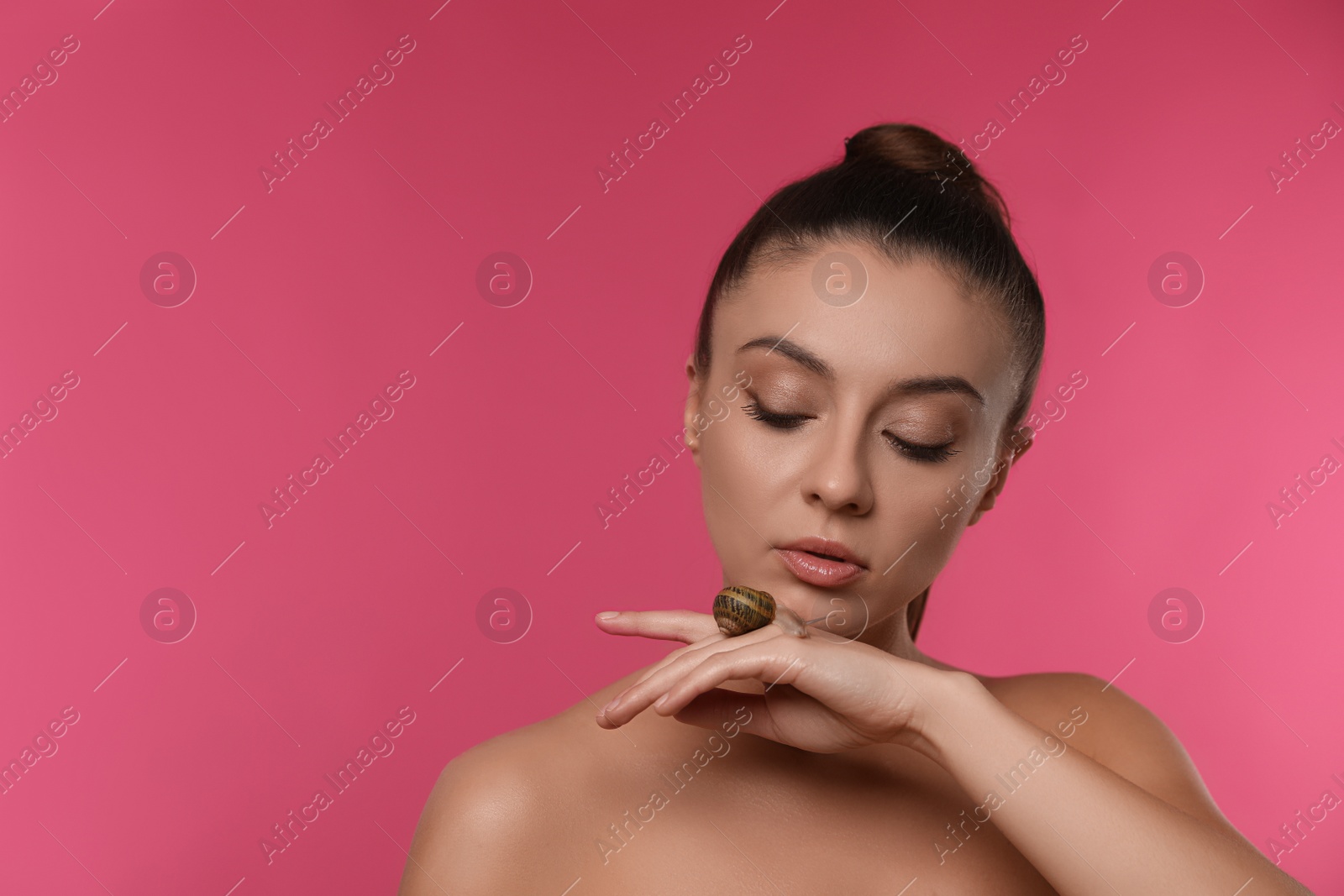 Photo of Beautiful young woman with snail on her hand against pink background. Space for text