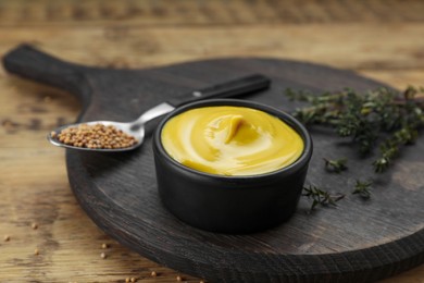 Photo of Delicious mustard, seeds and thyme on wooden table, closeup