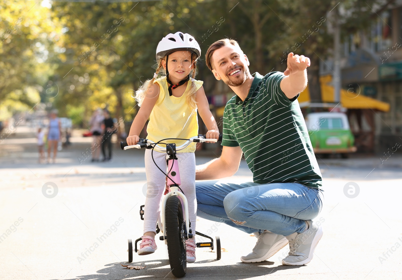 Photo of Father teaching daughter to ride bicycle on street