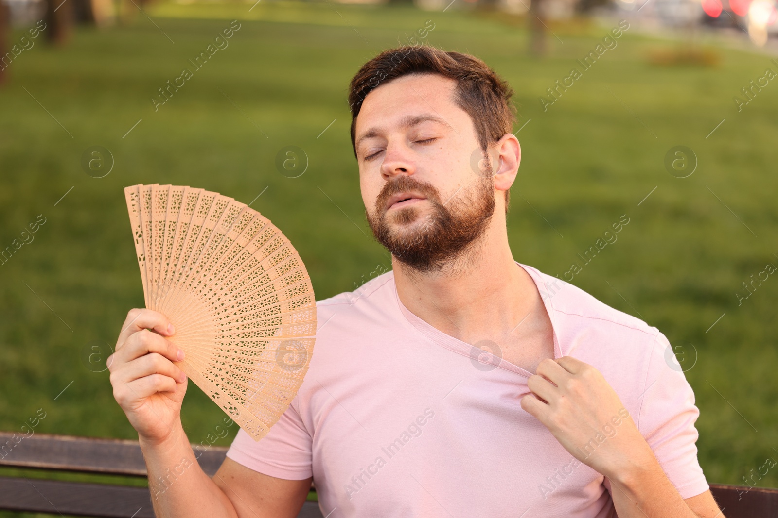 Photo of Man with hand fan suffering from heat outdoors