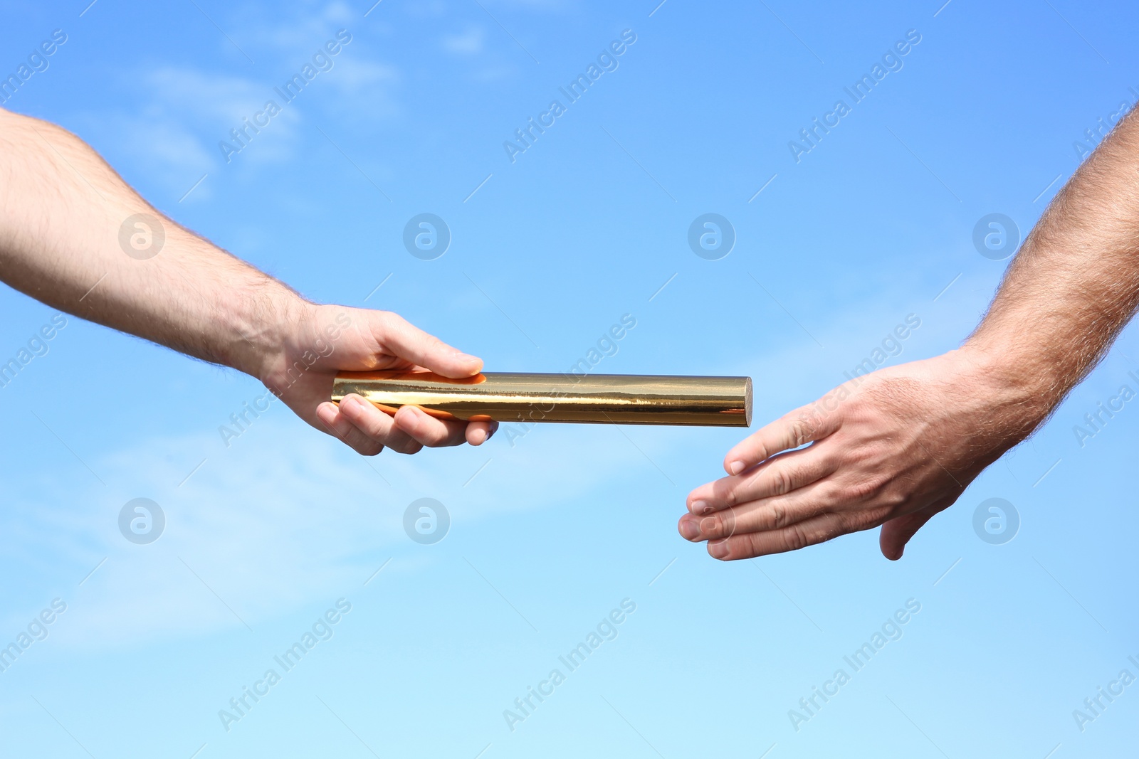 Photo of Man passing baton to his partner against blue sky, closeup