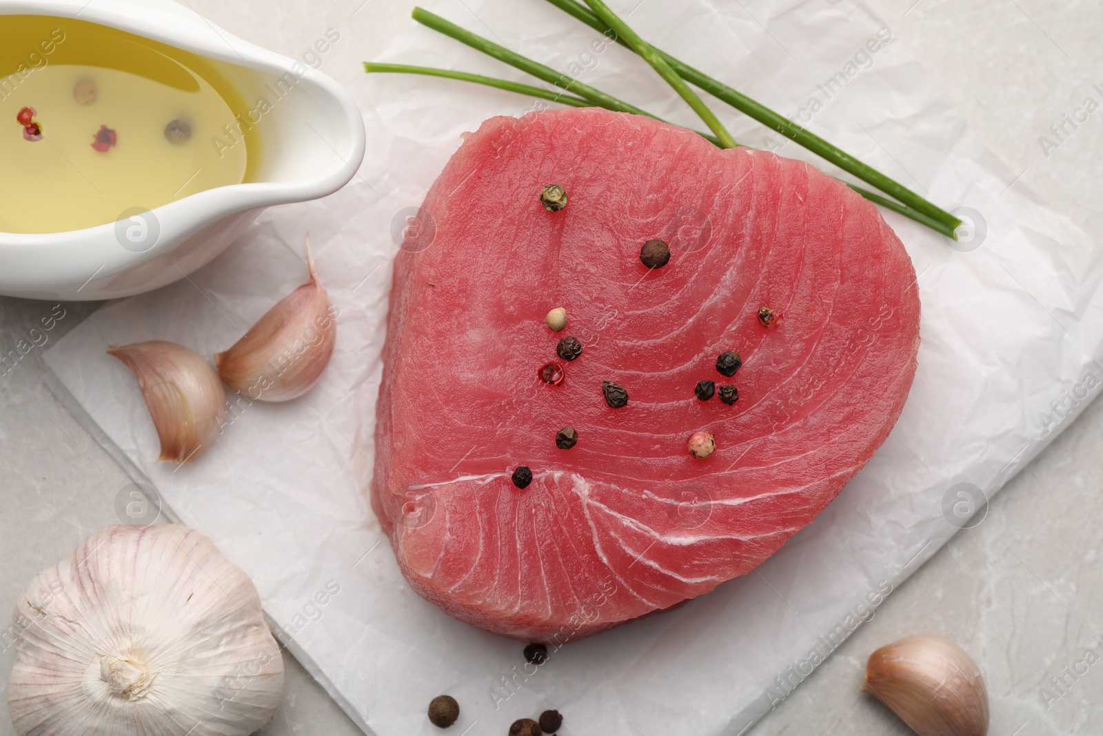 Photo of Raw tuna fillet and spices on light gray table, flat lay