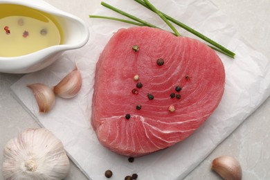 Raw tuna fillet and spices on light gray table, flat lay