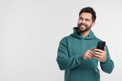 Photo of Happy young man using smartphone on white background, space for text