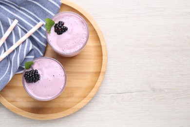 Photo of Delicious blackberry smoothie in glasses on white wooden table, top view. Space for text